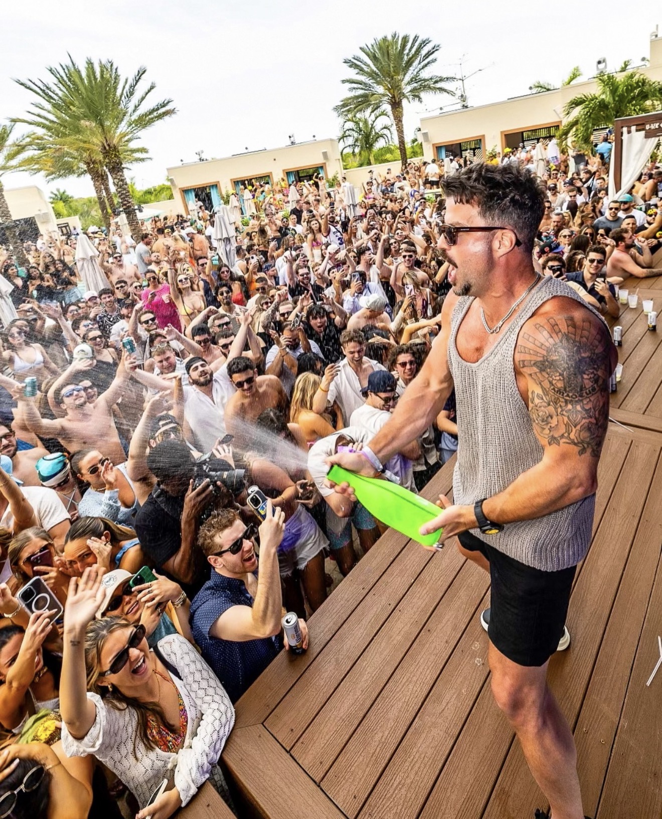 Daer Dayclub performer champagne spray packed crowd palm trees white cabanas daytime pool party